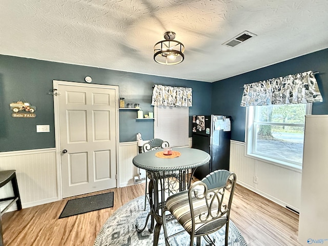 dining room with a wainscoted wall, wood finished floors, and visible vents