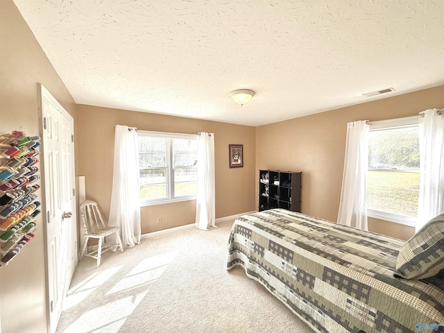 bedroom featuring light colored carpet, visible vents, a textured ceiling, and baseboards