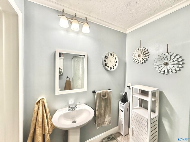 bathroom featuring crown molding, a sink, a textured ceiling, and baseboards