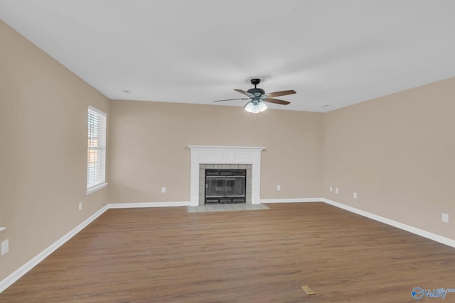 unfurnished living room featuring ceiling fan, hardwood / wood-style floors, and a tiled fireplace