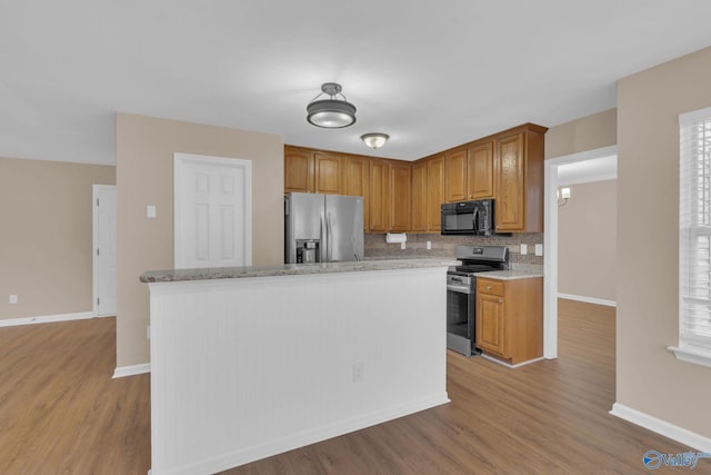 kitchen featuring light wood-type flooring, stainless steel appliances, decorative backsplash, and plenty of natural light