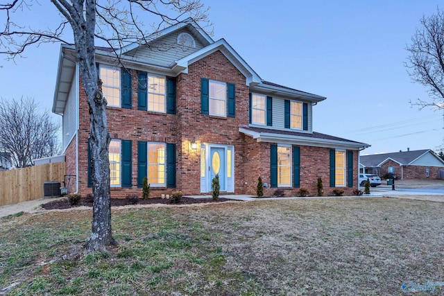 colonial-style house featuring central AC unit and a front yard