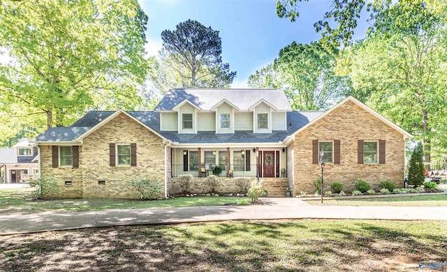 view of front of property featuring a porch, crawl space, brick siding, and a front lawn