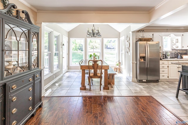 dining room featuring lofted ceiling, ornamental molding, wood finished floors, a chandelier, and baseboards