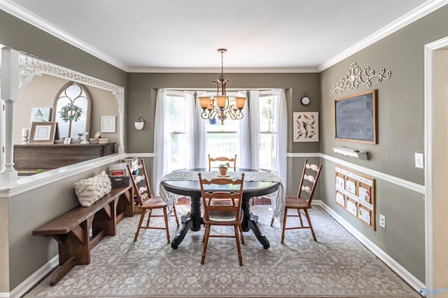 carpeted dining area featuring baseboards, ornamental molding, and an inviting chandelier