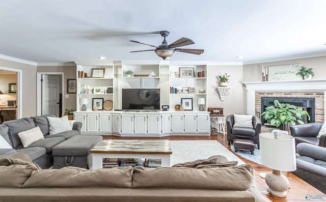 living area featuring a brick fireplace, ceiling fan, ornamental molding, and wood finished floors