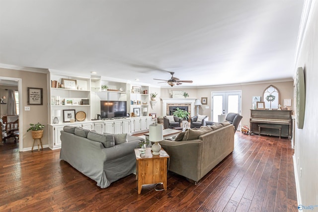 living room featuring dark wood-type flooring, a fireplace, baseboards, french doors, and crown molding