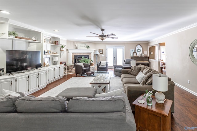 living area with french doors, crown molding, dark wood-type flooring, a brick fireplace, and baseboards