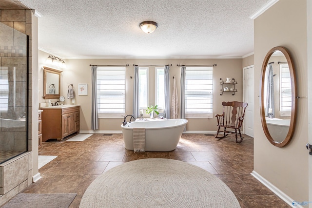 bathroom with a textured ceiling, a freestanding tub, vanity, tiled shower, and crown molding