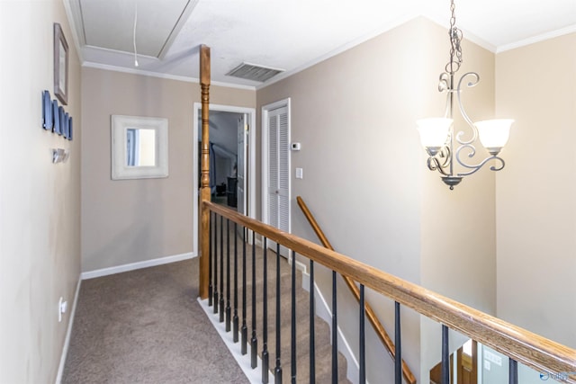 hall with carpet floors, crown molding, visible vents, attic access, and an upstairs landing