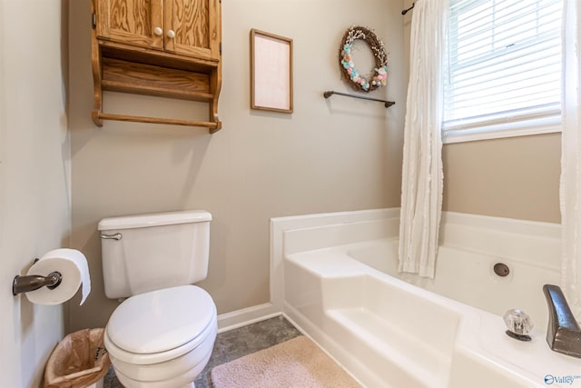 full bathroom with toilet, a garden tub, and baseboards