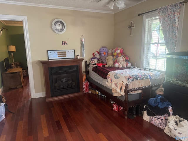 bedroom featuring crown molding, baseboards, a glass covered fireplace, and wood finished floors