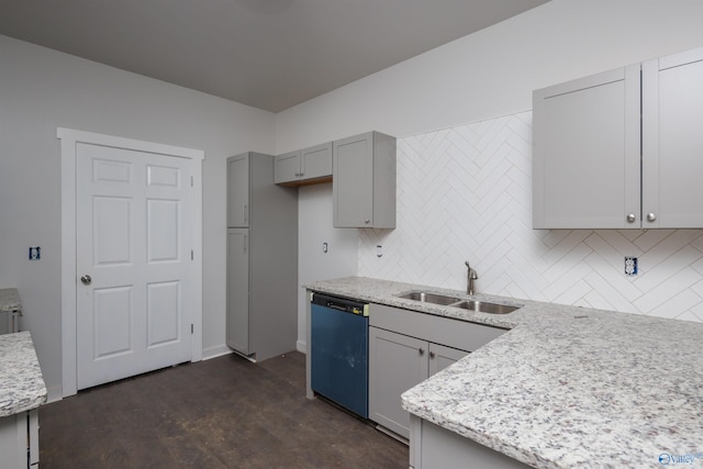 kitchen with light stone counters, gray cabinetry, a sink, backsplash, and dishwasher