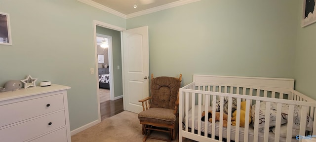 bedroom featuring a nursery area, light carpet, baseboards, and crown molding