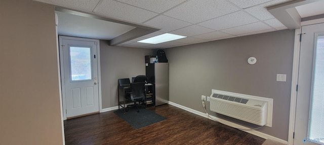 office space with baseboards, a drop ceiling, dark wood-style flooring, and a wall mounted AC