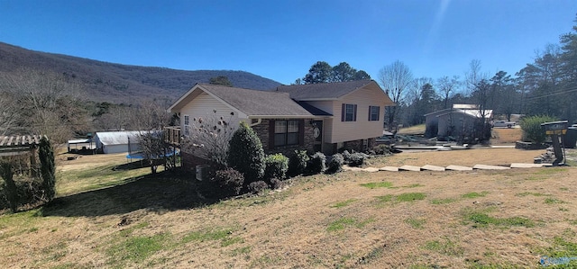 view of property exterior featuring stone siding, a mountain view, and a yard