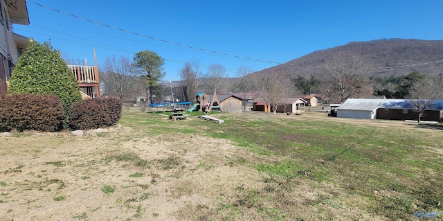 view of yard with a trampoline, a mountain view, and a playground