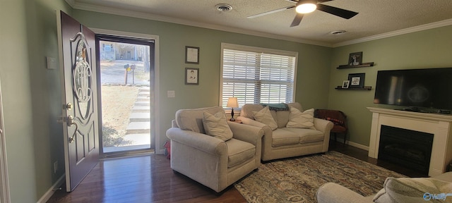 living room with a textured ceiling, dark wood finished floors, visible vents, and crown molding