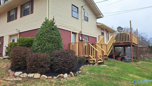 view of side of home featuring stairway, a yard, and a wooden deck