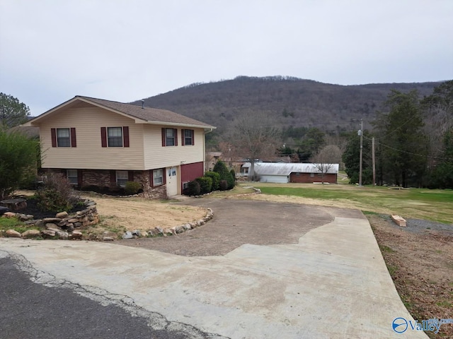 view of front of property featuring brick siding, a mountain view, driveway, and a front lawn