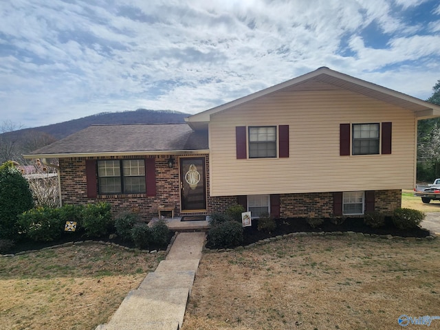 split level home with a front yard and brick siding