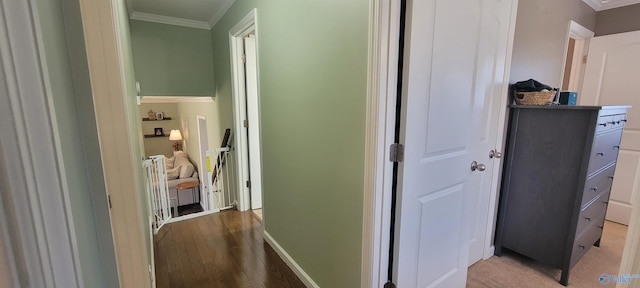 hall with light wood finished floors, ornamental molding, and baseboards