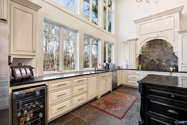 kitchen featuring dark tile patterned floors, sink, stainless steel dishwasher, cream cabinets, and wine cooler