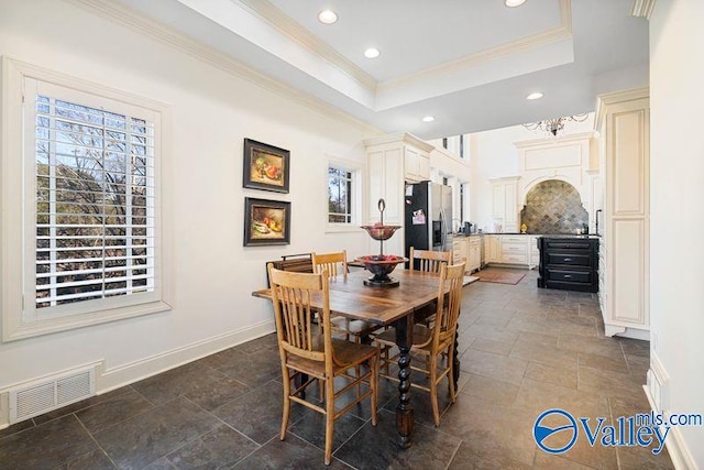 tiled dining area featuring ornamental molding and a raised ceiling