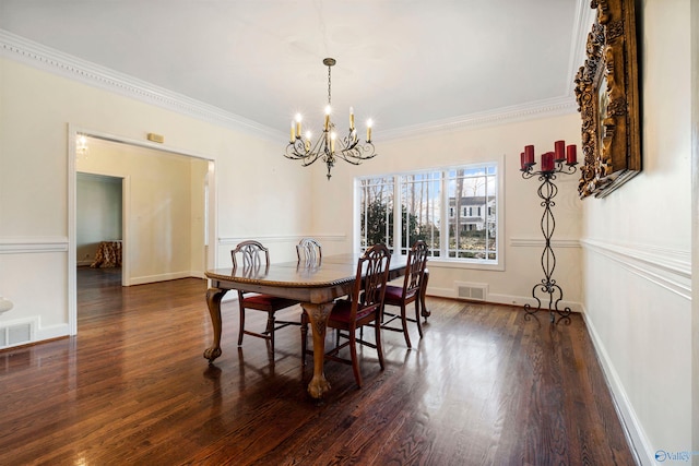 dining area featuring dark wood-type flooring, crown molding, and a chandelier