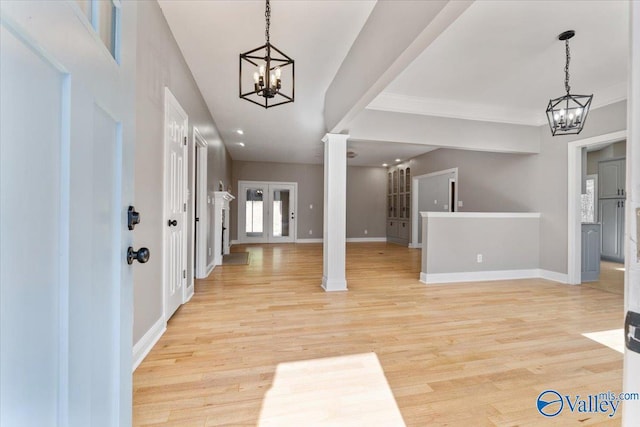 entrance foyer with ornate columns, a notable chandelier, and light hardwood / wood-style floors