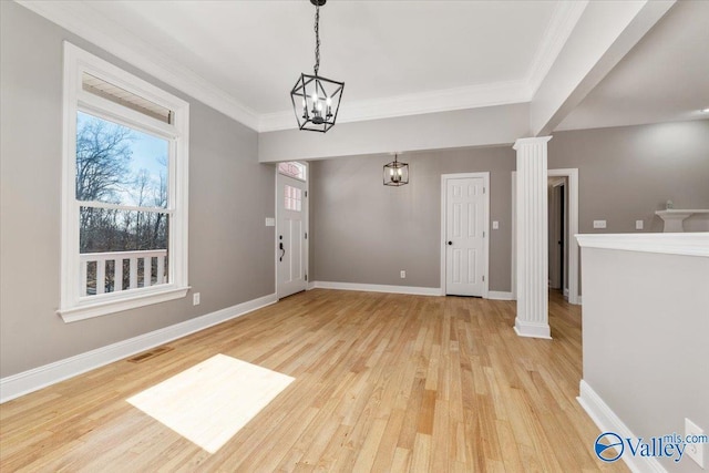 interior space with decorative columns, crown molding, an inviting chandelier, and light hardwood / wood-style flooring