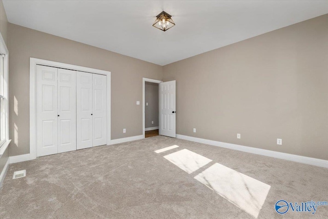 unfurnished bedroom featuring light colored carpet and a closet