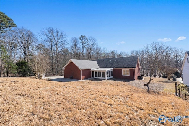 back of property with a sunroom and a lawn