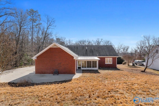 rear view of property with a patio area, a sunroom, and a lawn