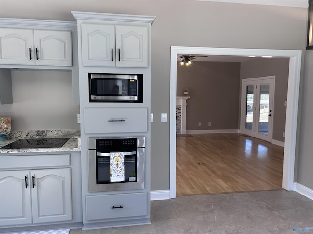 kitchen with white cabinetry, appliances with stainless steel finishes, light stone countertops, and french doors