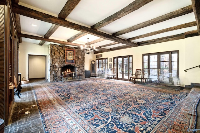 living area featuring baseboards, beam ceiling, a stone fireplace, french doors, and a chandelier