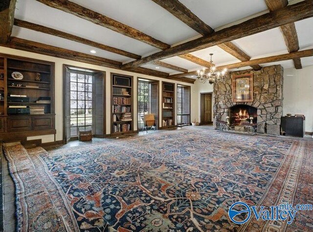 living room featuring beamed ceiling, a fireplace, built in shelves, a chandelier, and coffered ceiling