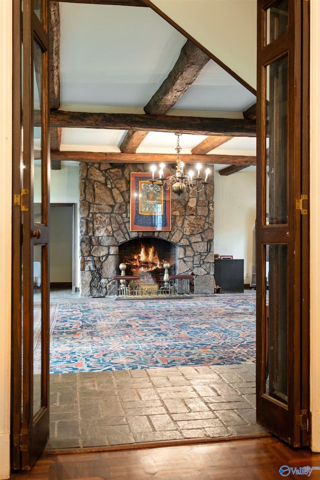 unfurnished living room featuring beamed ceiling, a notable chandelier, and a fireplace