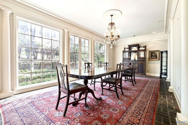 dining room featuring baseboards, a chandelier, decorative columns, ornamental molding, and brick floor