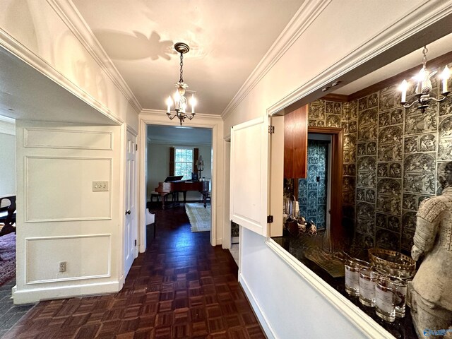 corridor with crown molding, a notable chandelier, and dark parquet floors