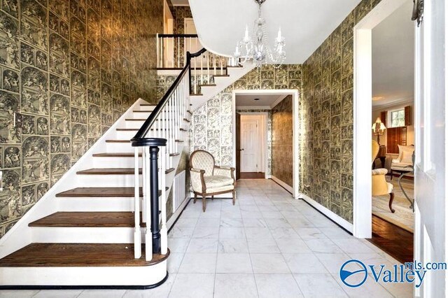 stairway with tile walls, tile patterned floors, a chandelier, and ornamental molding