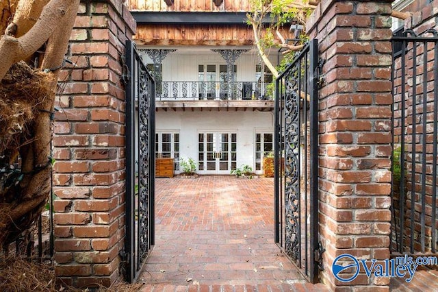 view of exterior entry with a balcony and french doors