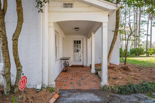 entrance to property with visible vents and brick siding