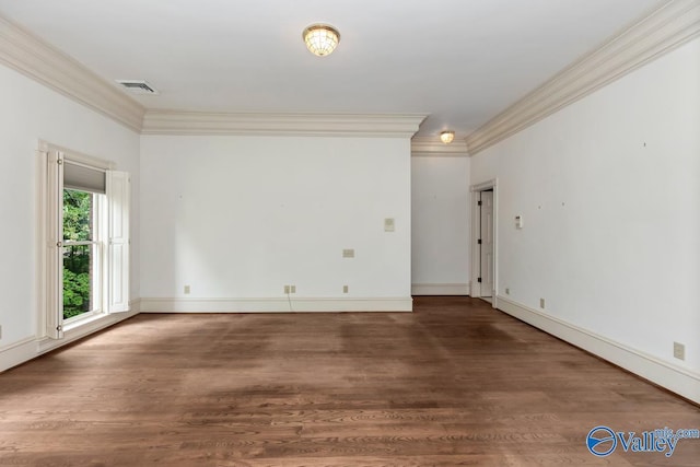 spare room with wood finished floors, visible vents, crown molding, and baseboards
