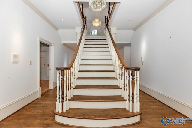 stairs with ornamental molding, wood finished floors, and baseboards