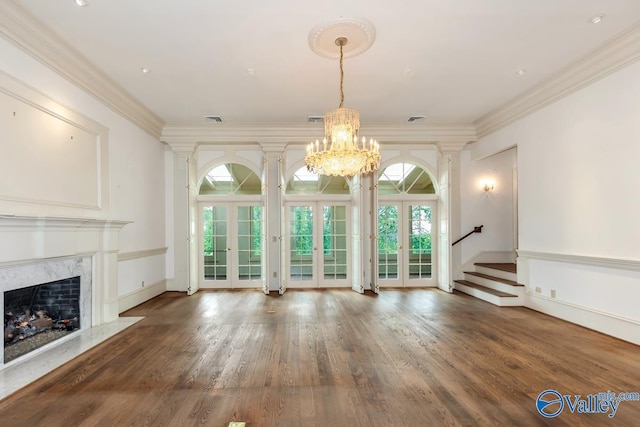 unfurnished living room featuring stairway, a fireplace, a notable chandelier, french doors, and wood finished floors