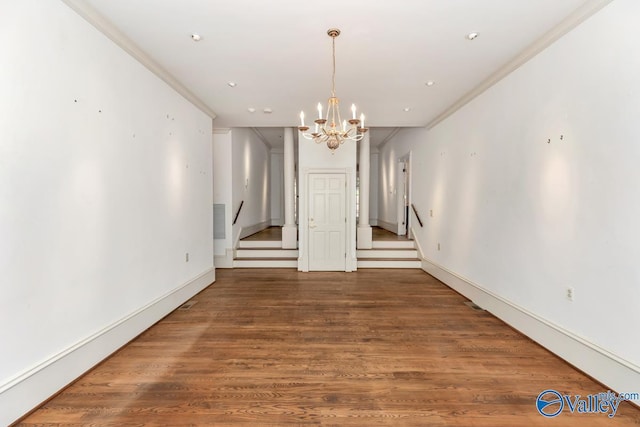 unfurnished dining area with ornamental molding, a notable chandelier, wood finished floors, and baseboards