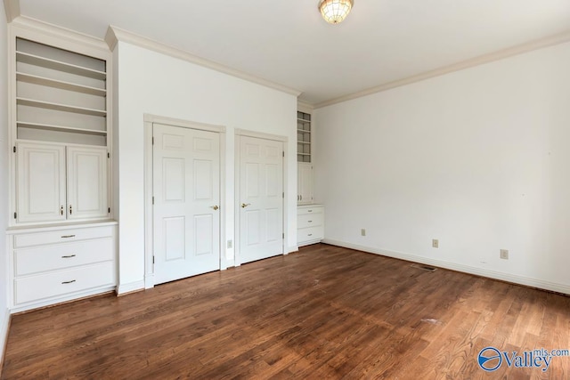 unfurnished bedroom featuring crown molding, visible vents, baseboards, dark wood-type flooring, and two closets