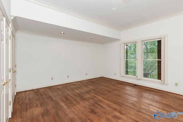 unfurnished room featuring wood finished floors, crown molding, visible vents, and baseboards