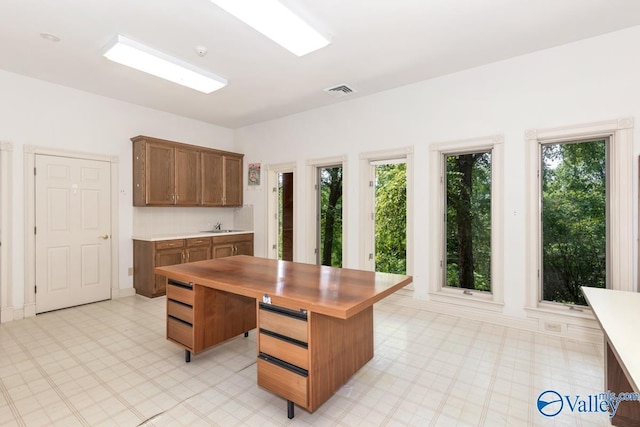 kitchen featuring wooden counters, a sink, plenty of natural light, and light floors